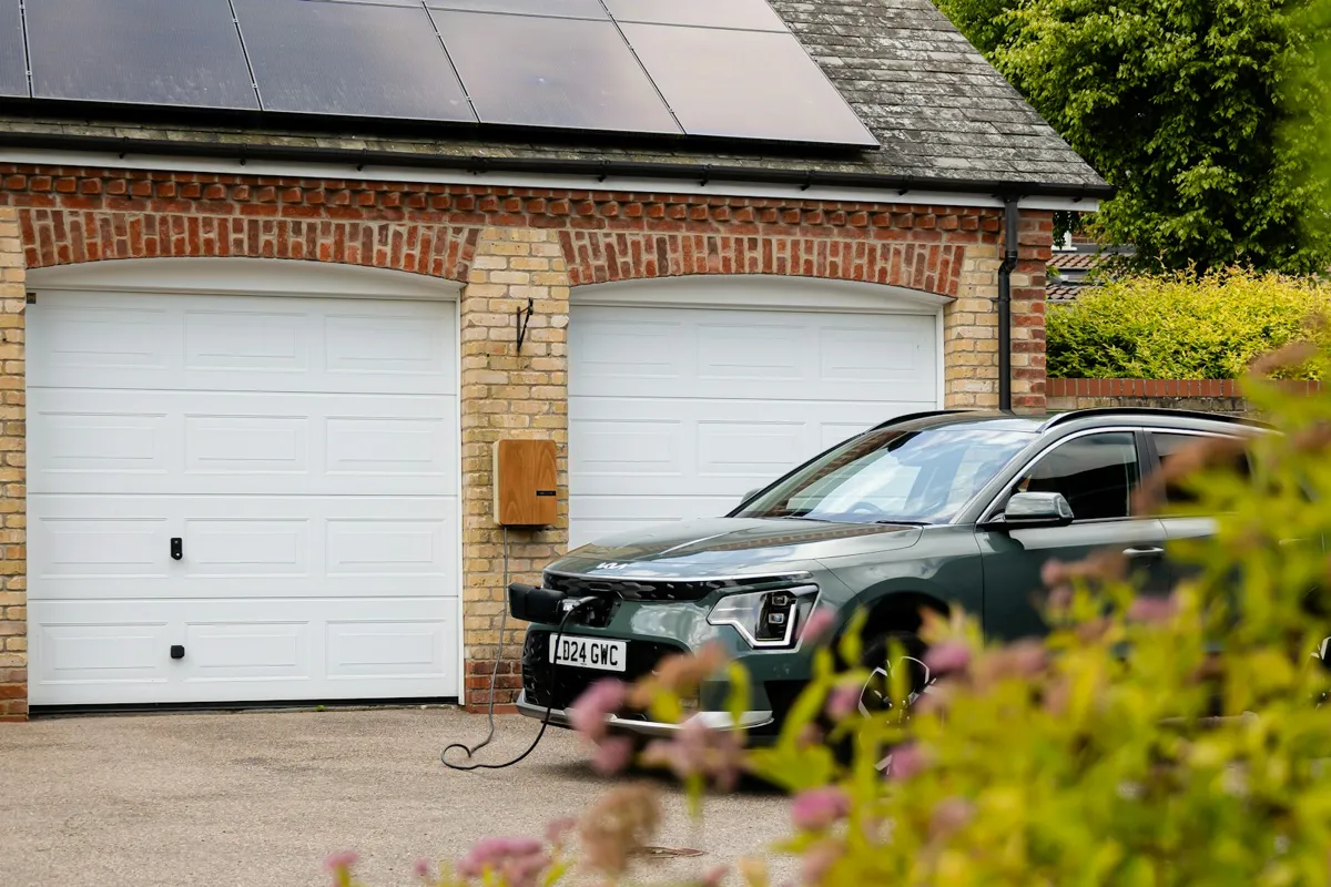 Two white garage doors with an electric car parked in front